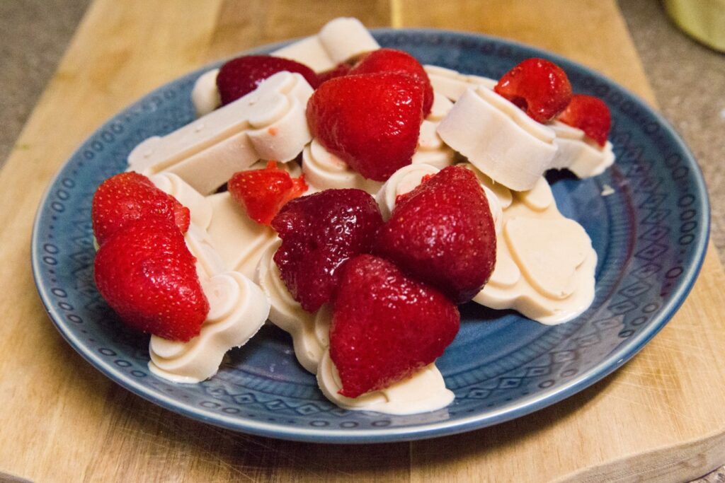PB&J Pupcicles on a blue kitchen plate with strawberries on top.