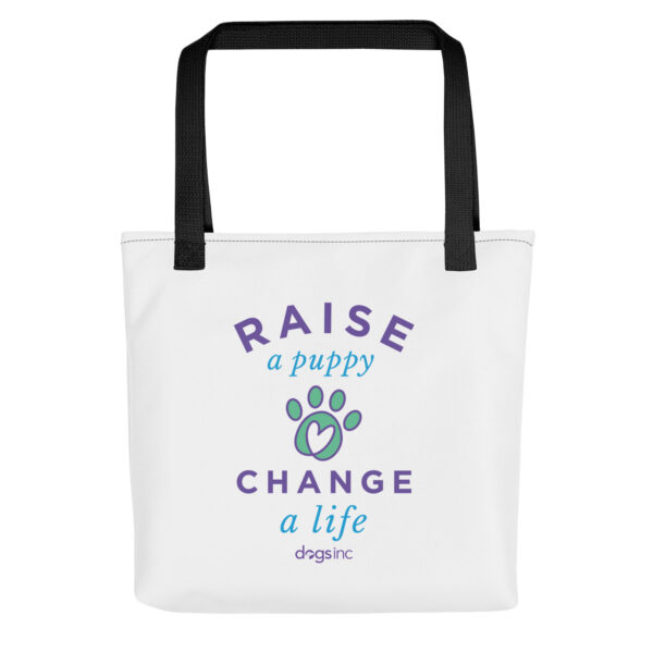 A white tote bag with a graphic paw print and 'Raise a Puppy Change a Life' text in purple and blue.