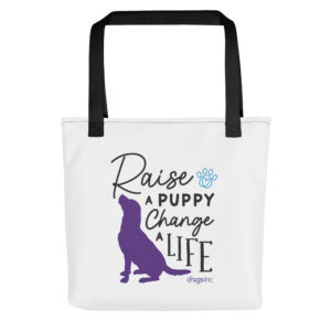A white tote bag with a dog graphic in purple and 'Raise a Puppy Change a Life' text in black.